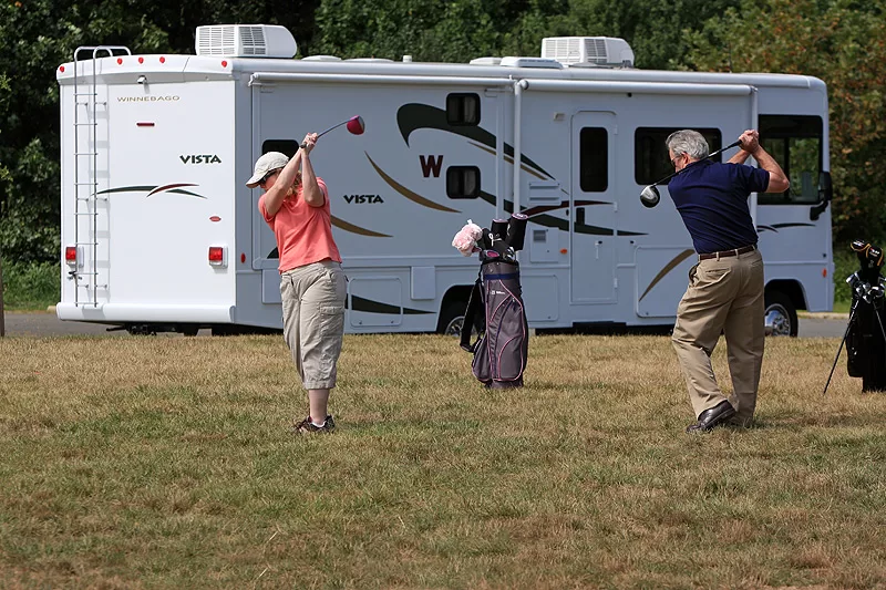 rv parked in background and people playing golf